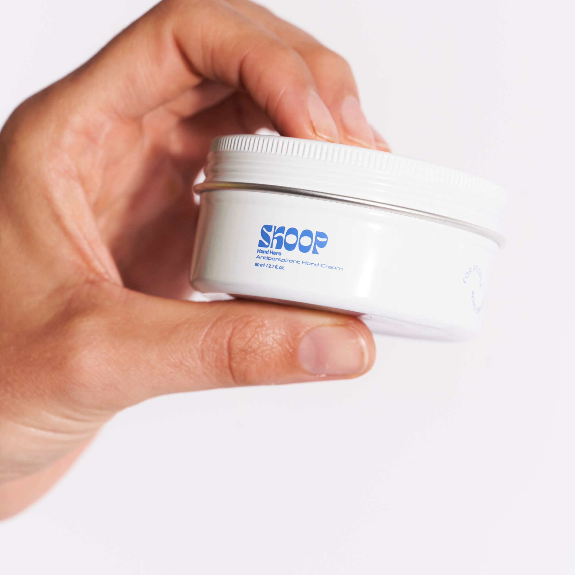 Skoop Skincare, Hand Hero Antiperspirant Hand Cream. Hand holding Skoop Skincare Tin with Skoop logo visible
